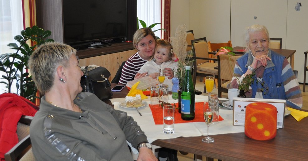 3 Personen und 1 Kleinkind sitzen beisammen.