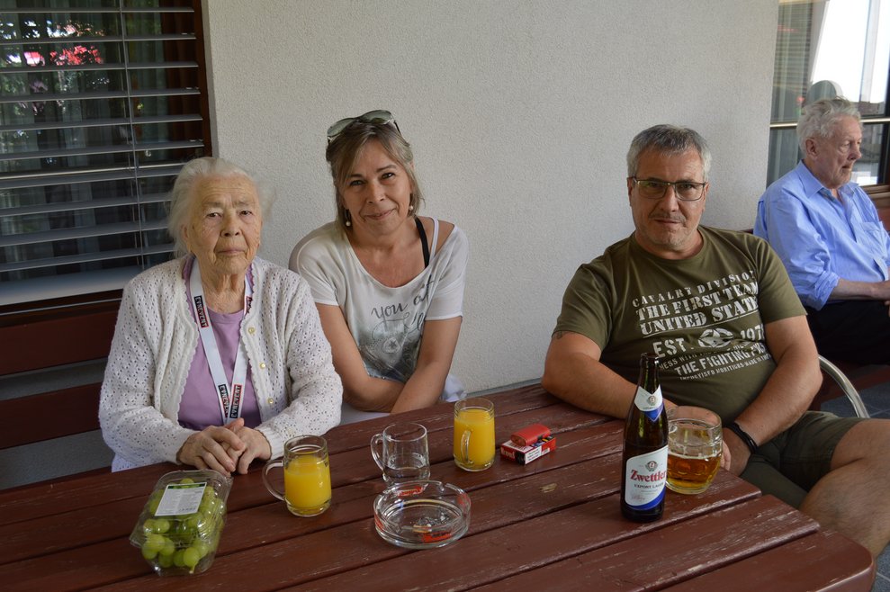 Eine Frau und ein Mann sitzen neben einer Bewohnerin.
