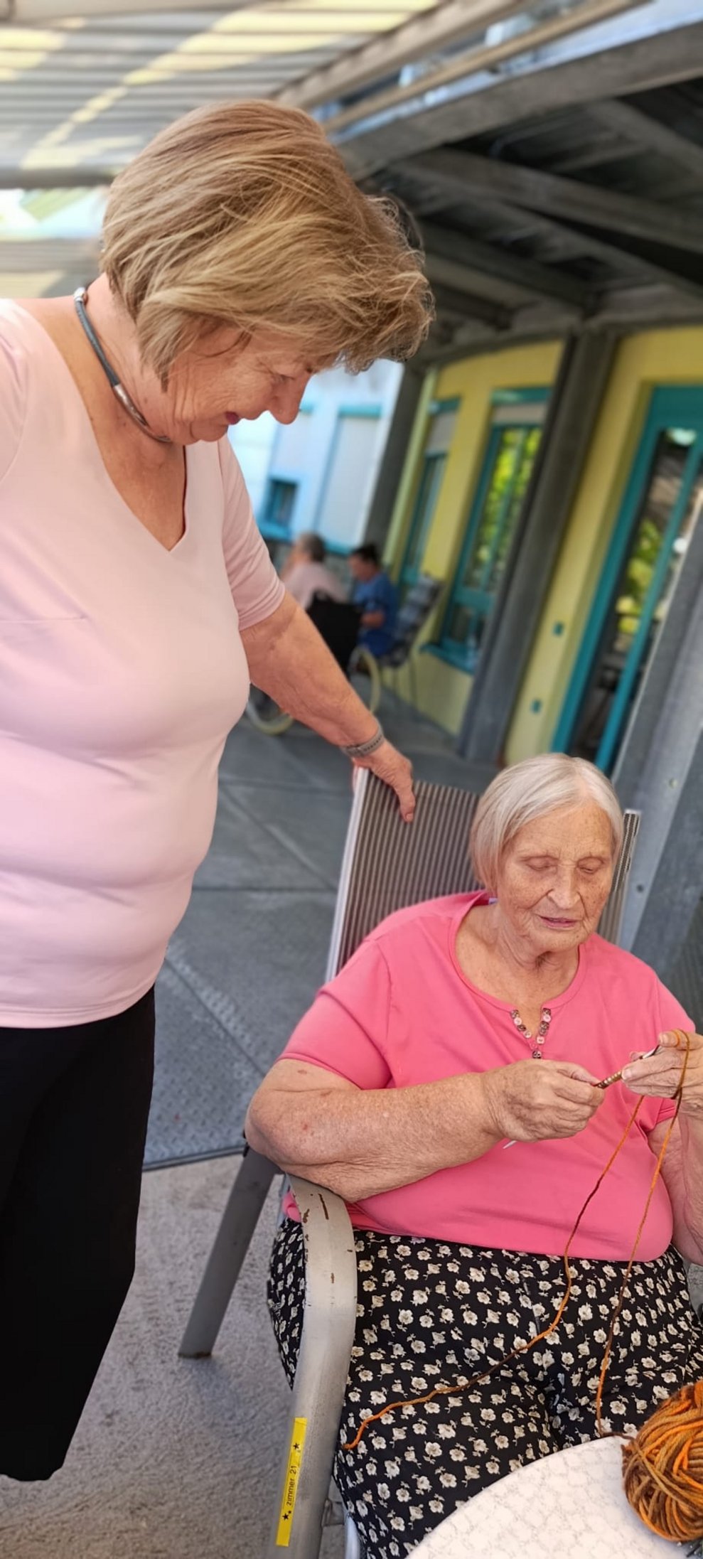 Bewohnerin häkelt. Frau steht.