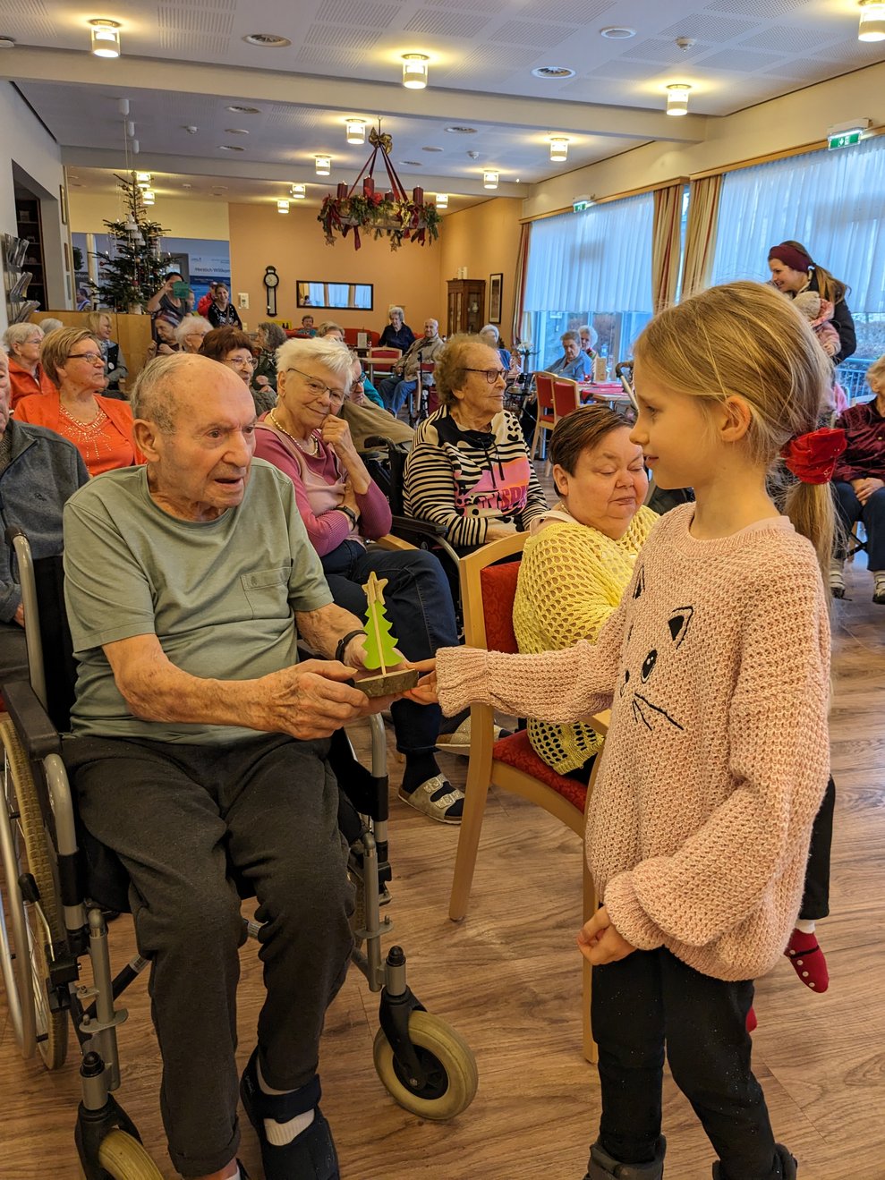 Lili übergibt eines ihrer Bäumchen an einen Bewohner.