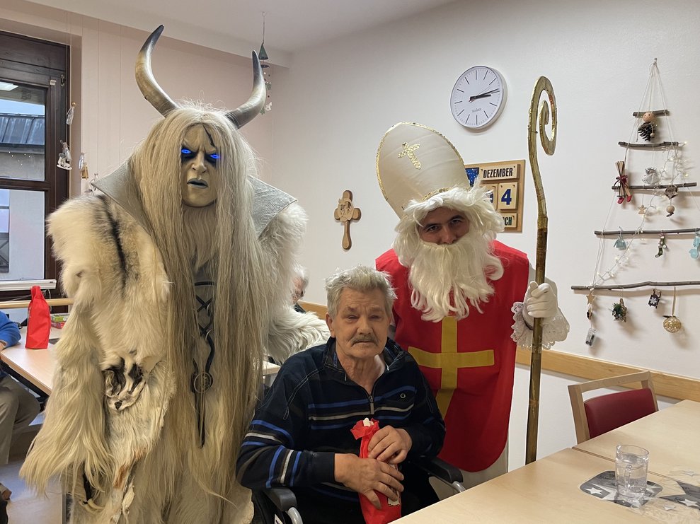 Nikolo und Krampus mit einem Mann. 