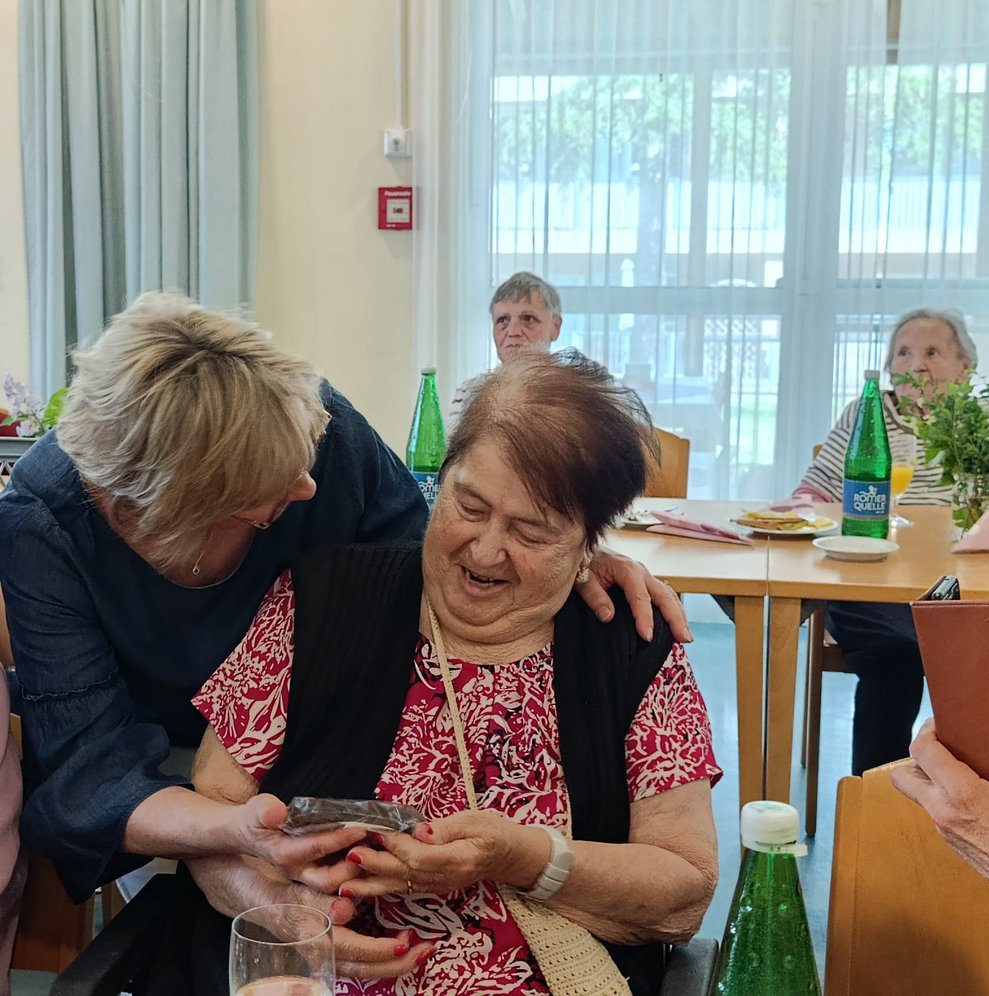 Pflegedirektorin gibt Bewohnerin Schokomuttertagsherz.