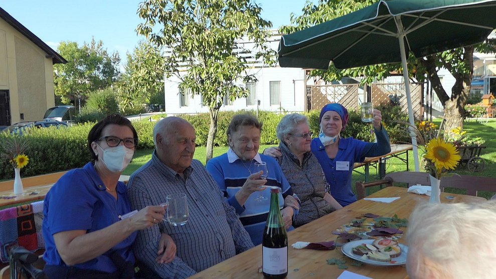Fünf Personen prosten mit Wein in die Kamera.