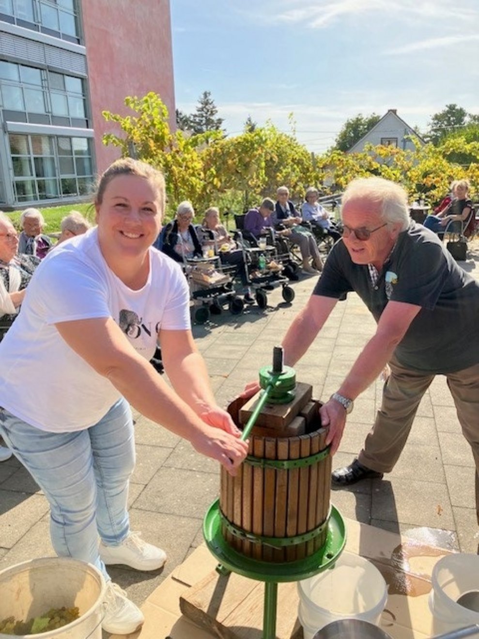 Mitarbeiterin und Ehrenamtlicher beim Weinpressen