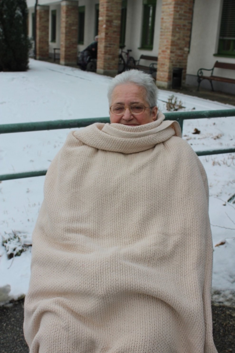 Eine Bewohnerin ist draußen beim Schnee.