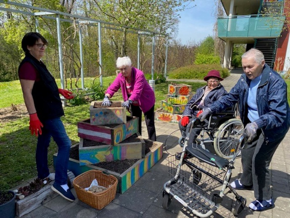 Bewohner mit ehrenamtliche beim Einpflanzen von den Kartoffeln