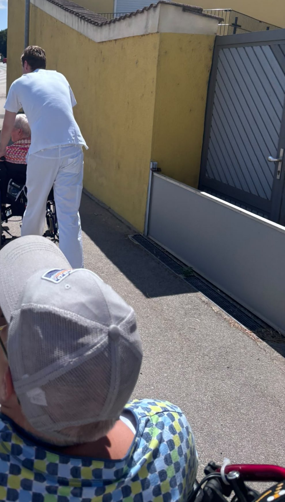 Auf den Weg zum Eis essen. Alltagsbegleiter schiebt Rollstuhl mit Bewohnerin.