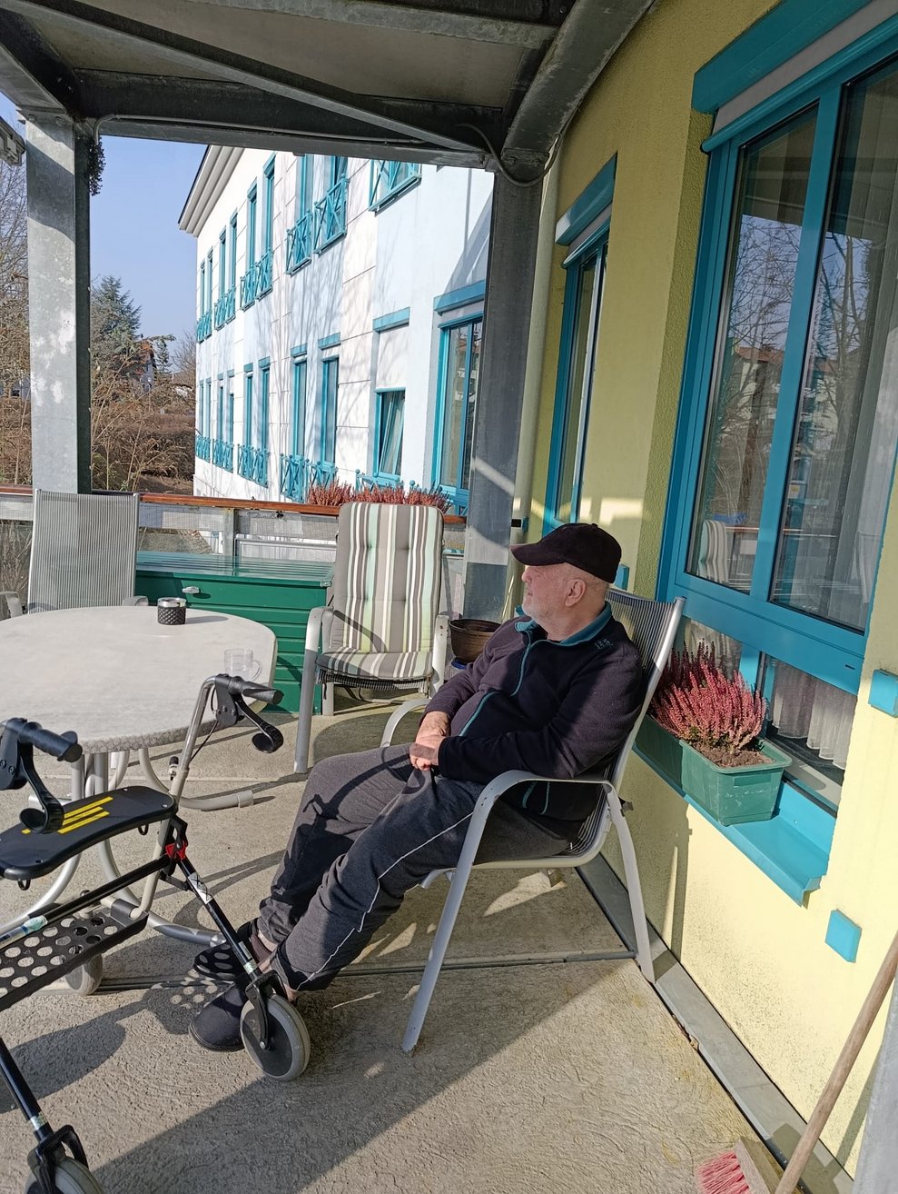Bewohner sitzt am Sessel auf Terrasse.