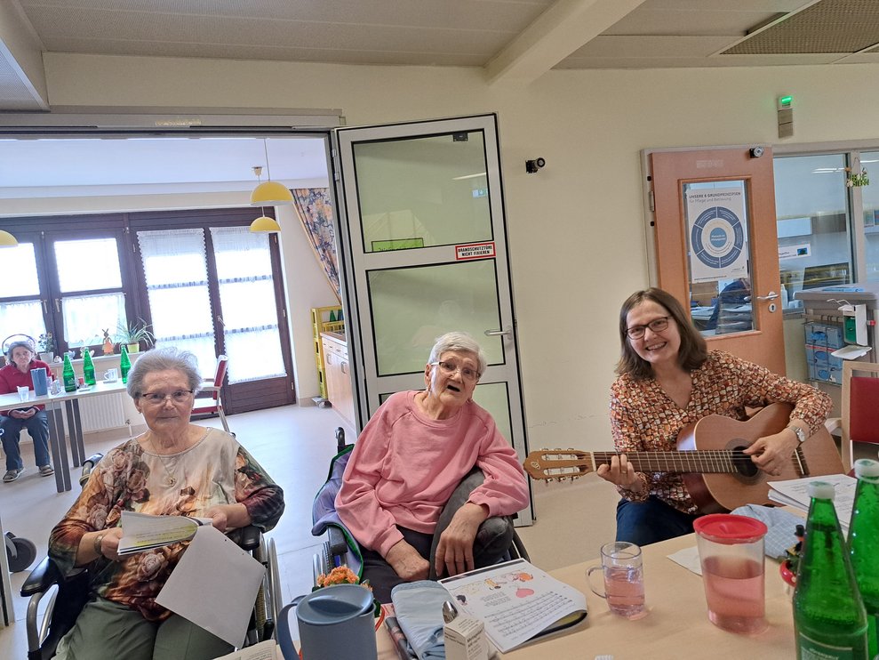 Drei Damen singen mit Gitarrenbegleitung. 