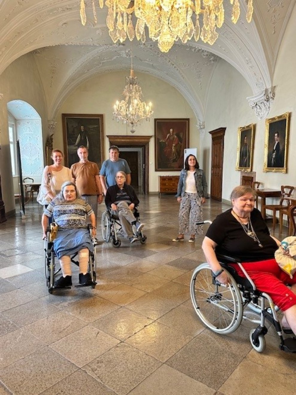 Bewohnerinnen und Bewohner und Pflegepersonal gehen durch die Bildergalerie.
