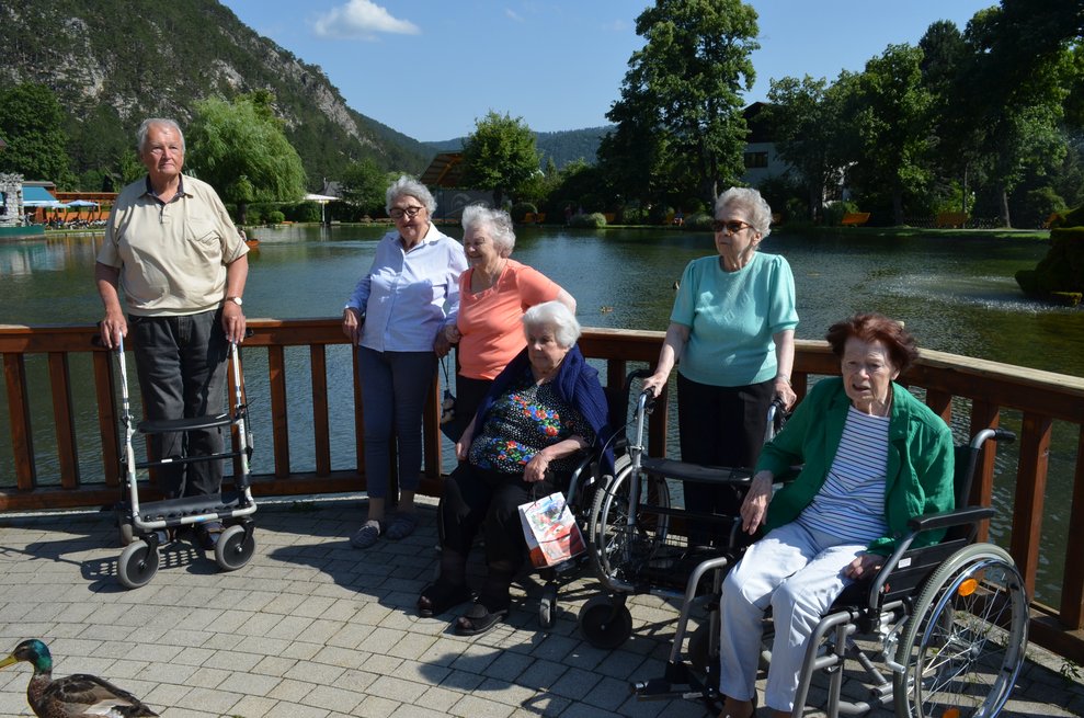 die Bewohner stehen vor dem Teich und lächeln glücklich