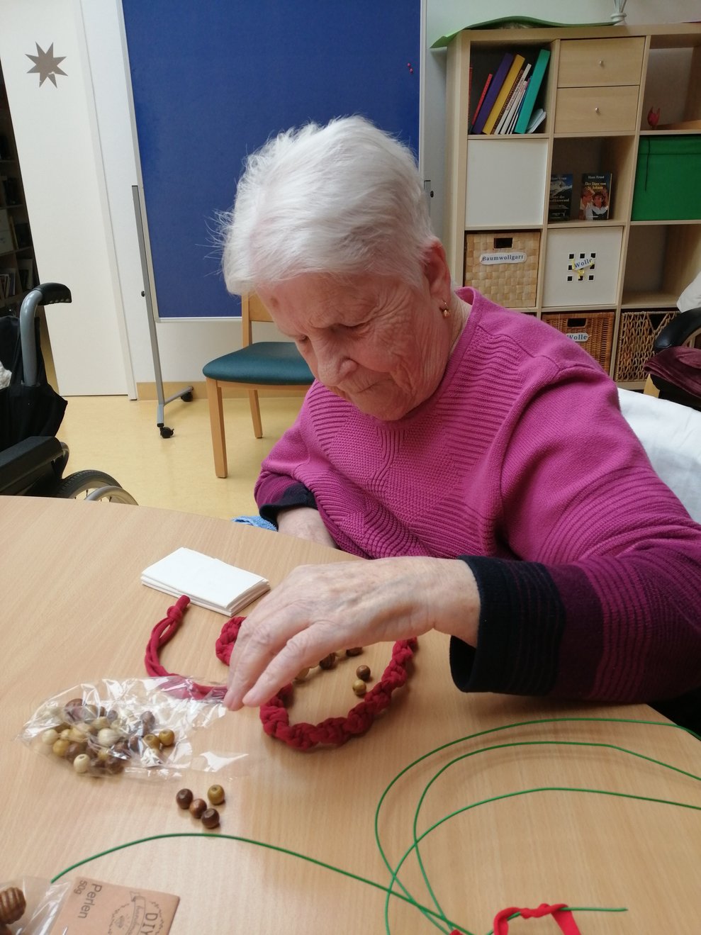 Frau L. sortiert die Holzperlen die an das Herz gehängt werden.