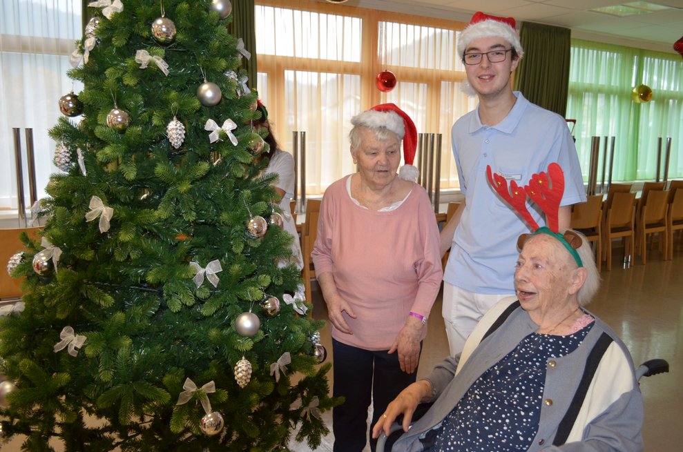 Mitarbeiter mit Bewohnerinnen vorm Christbaum