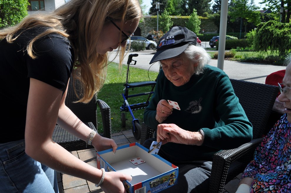 ein junges Mädchen lässt eine ältere Frau eine Spielkarte aus einer Schachtel ziehen