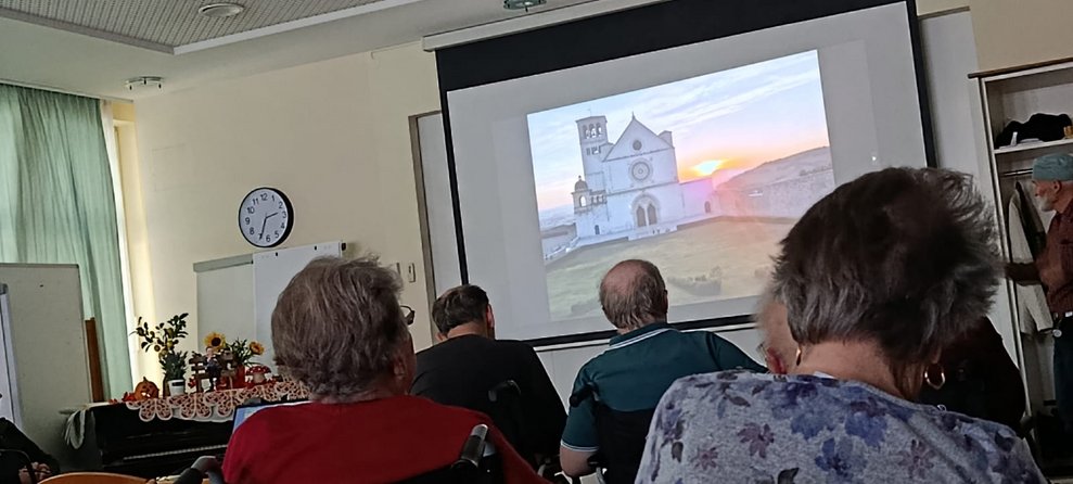 BewohnerInnen schauen auf Leinwand mit Foto.