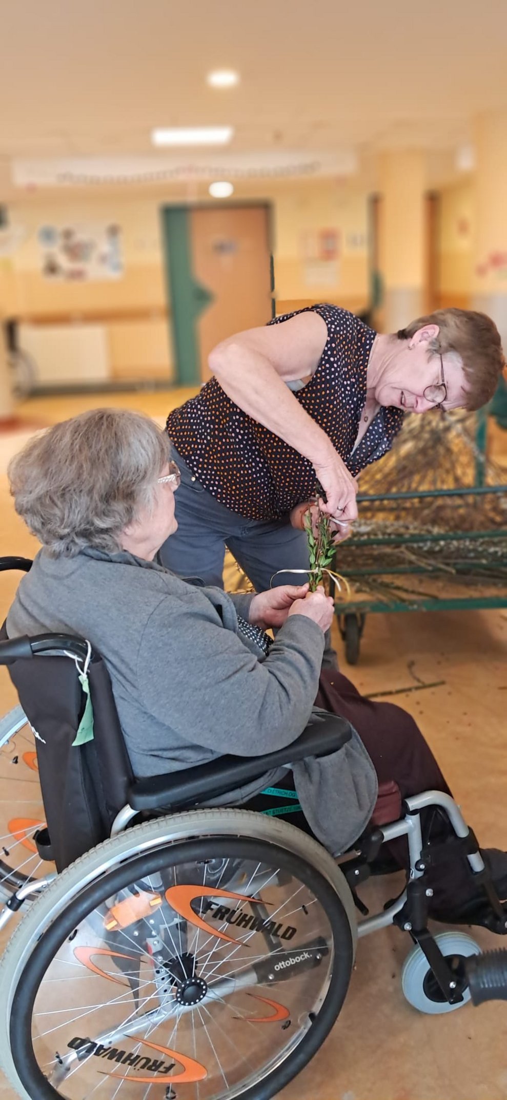 Bewohnerin und Frau beim Palmbuschen binden.