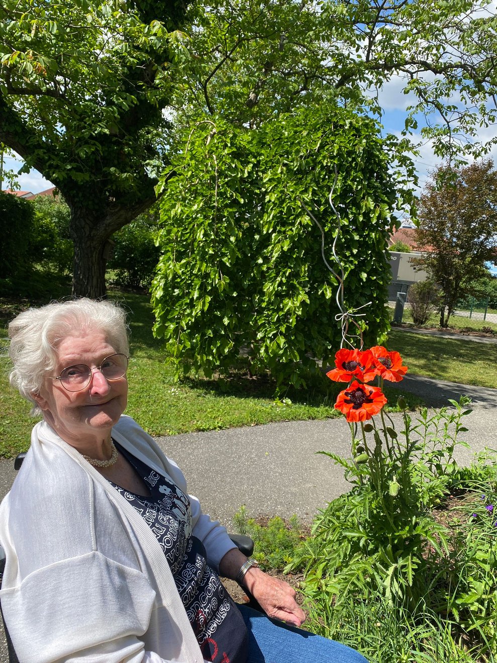 eine ältere Dame betrachtet eine rote Blume