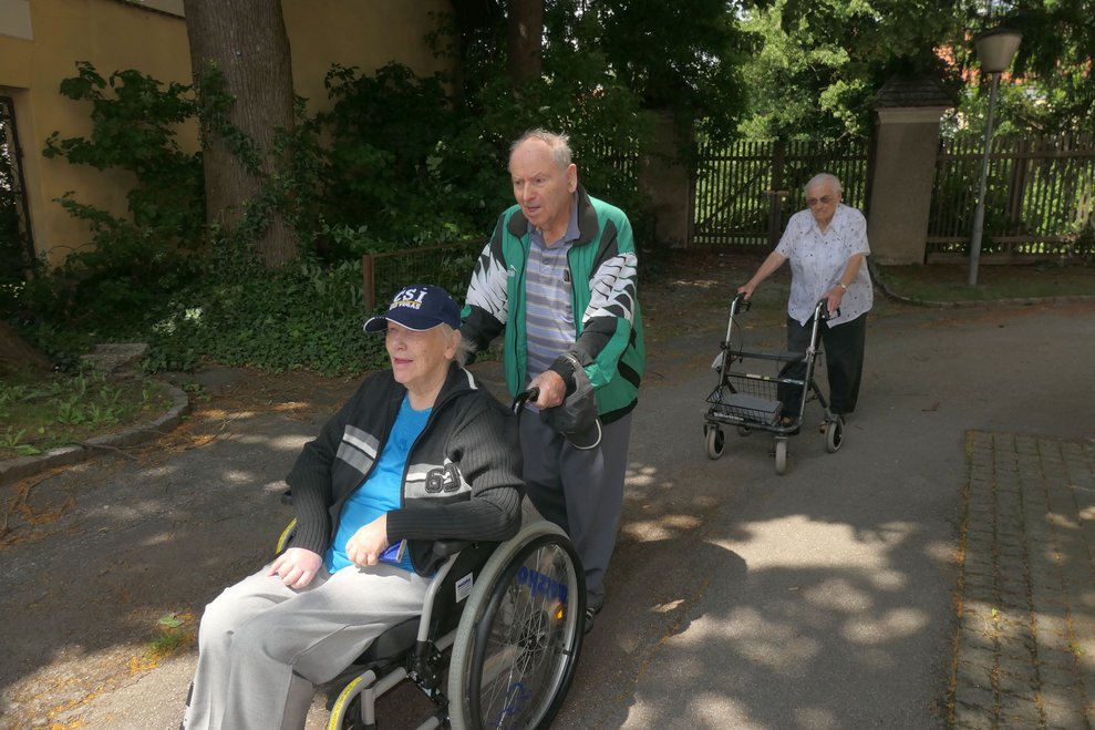 Drei Personen mit Rollstuhl, Rollator und zu fuß.