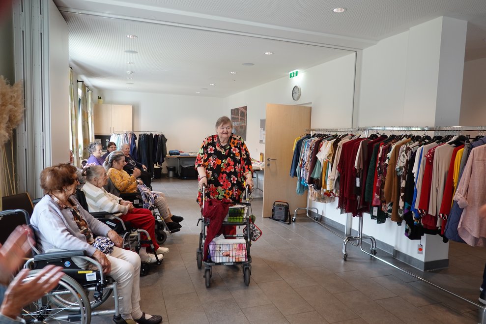 Eine Bewohnerin mit Rollator präsentiert ein Blumenkleid