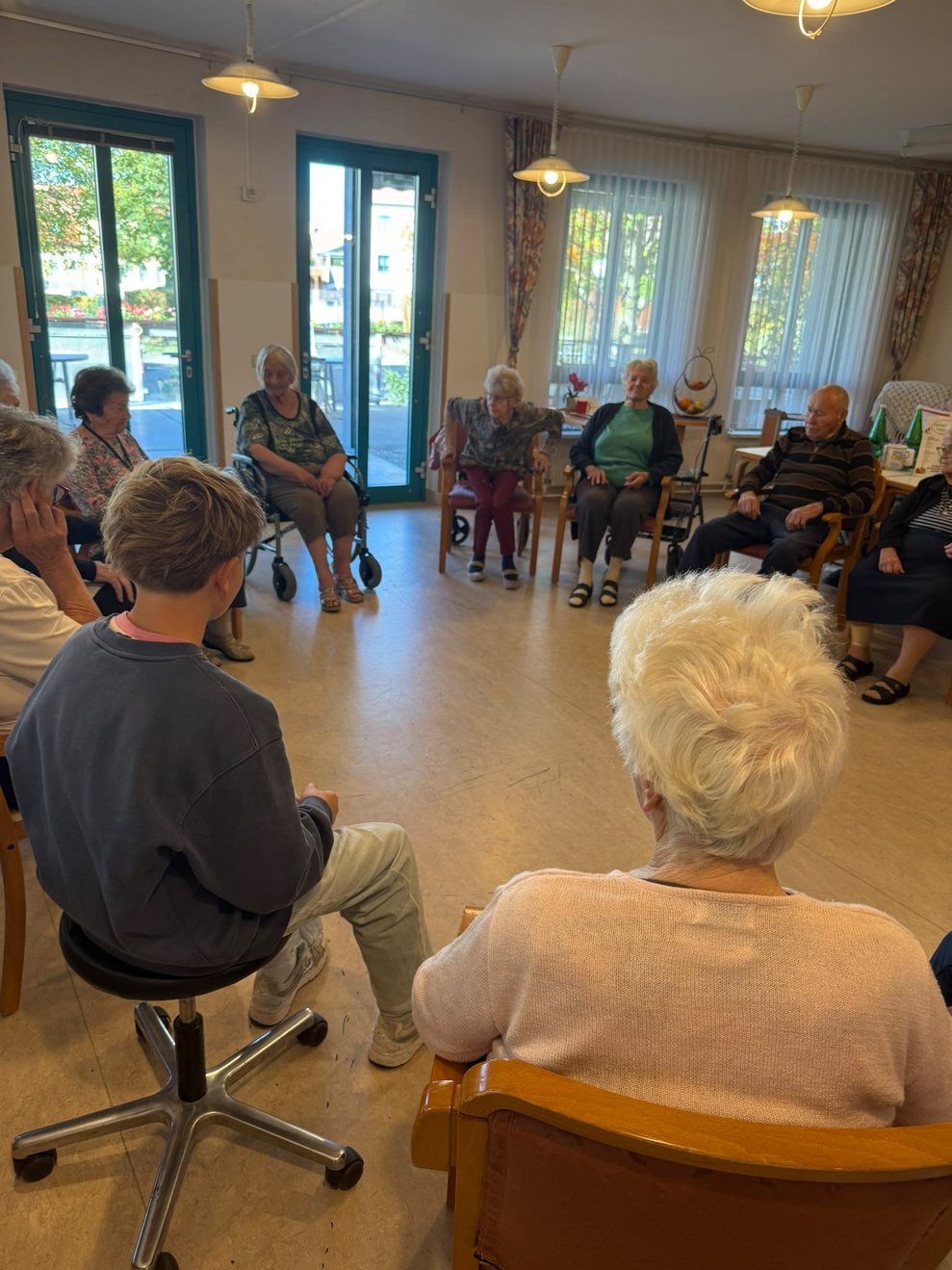 BewohnerInnen und Praktikant sitzen im Kreis.