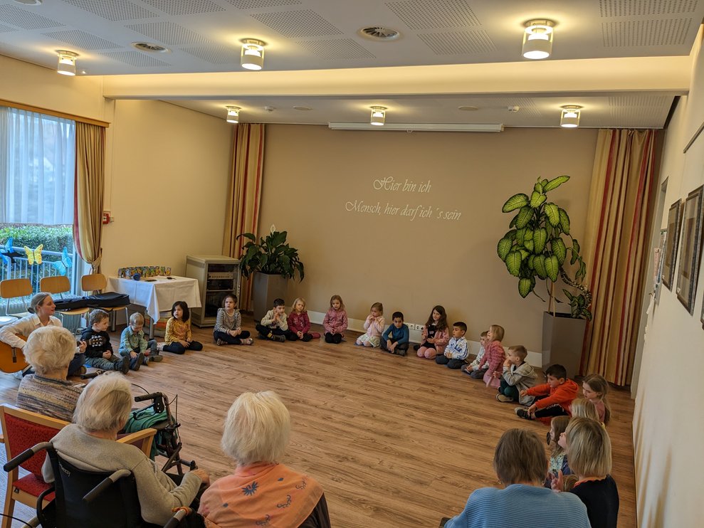 Die Kinder sitzen im Halbkreis auf dem Boden