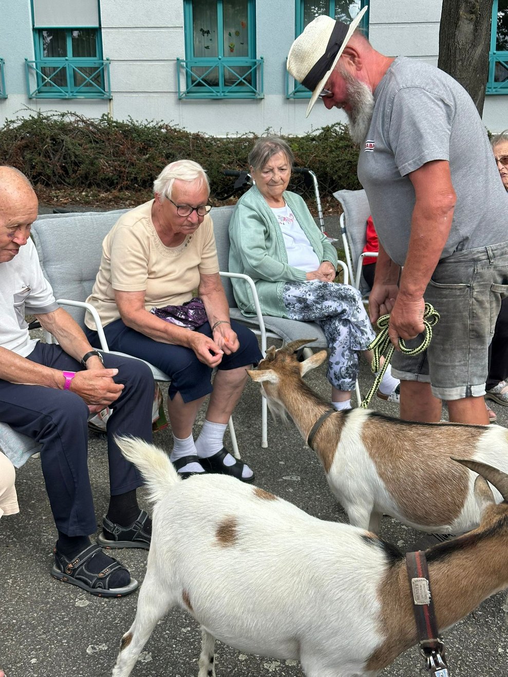 Sitzender Bewohner mit Ziege. Mann haltet Ziege an der Leine.