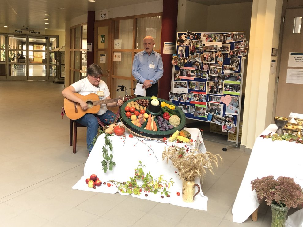 Eine Frau mit Gitarre und ein Mann hinter dem Gabentisch. 