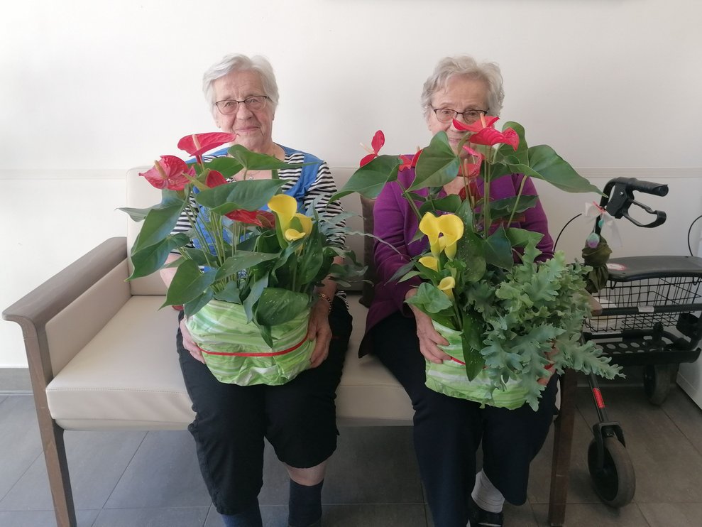 Frau Eckler und Frau Kornfeld nehmen stellvertretend für die Bewohner und Bewohnerinnen der Wohnbereiche Seerose und Sonne die Blumengrüße entgegen.