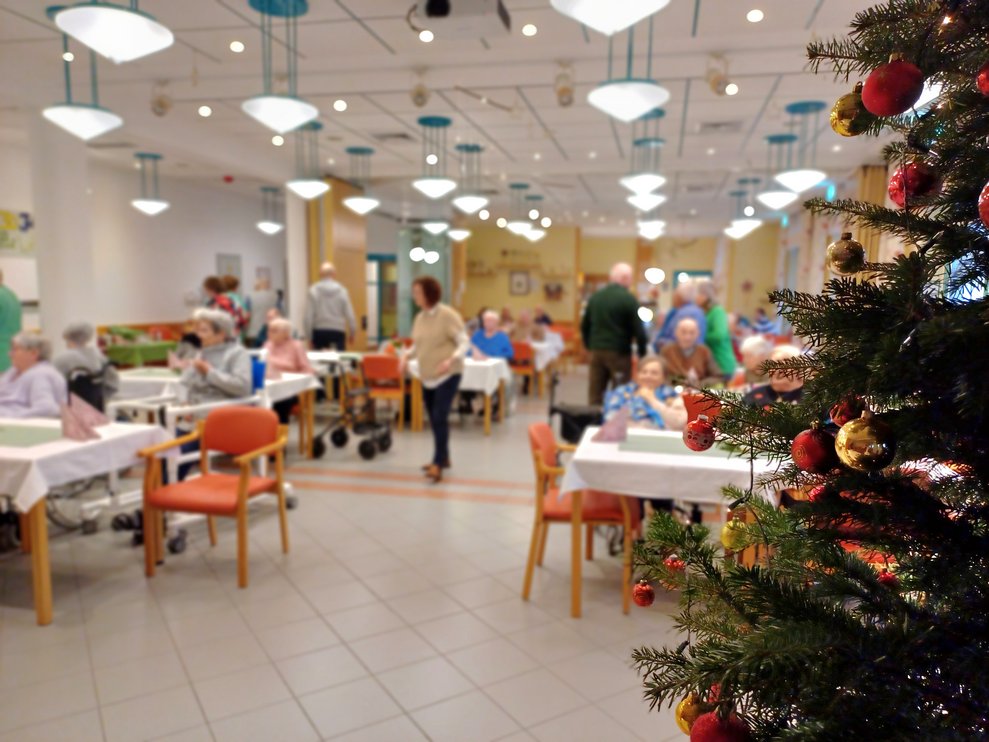 Christbaum und im Hintergrund die gesellige Rund bei der Kaffeejause