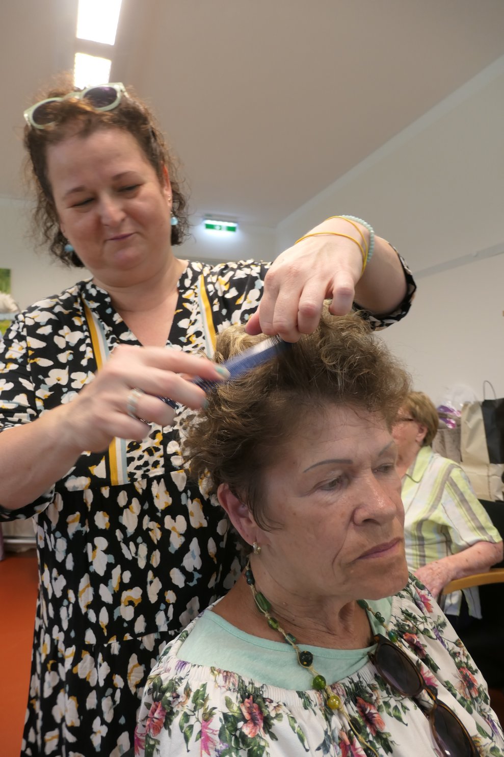 Die Frisörin macht einer Dame die Haare.