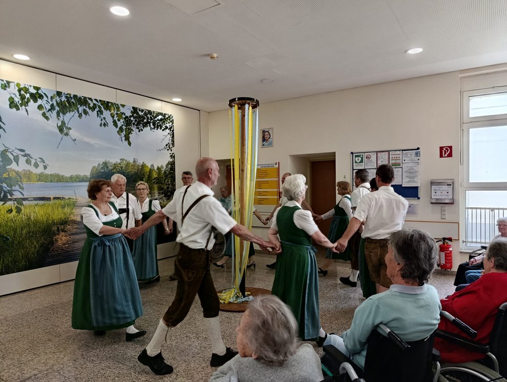 MitgliederInnen der Volkstanzgruppe Rosenburg/Mold tanzen um die Stange mit Bänder herum.
