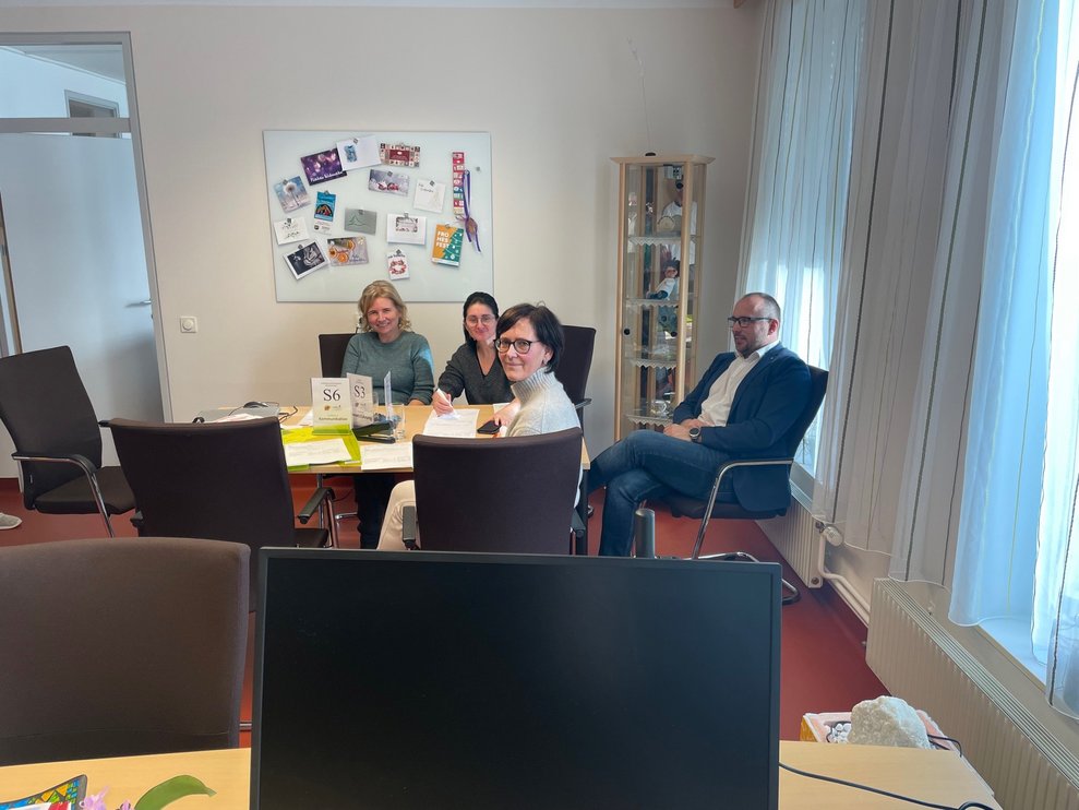 Vier Personen sitzen bei einem Tisch.