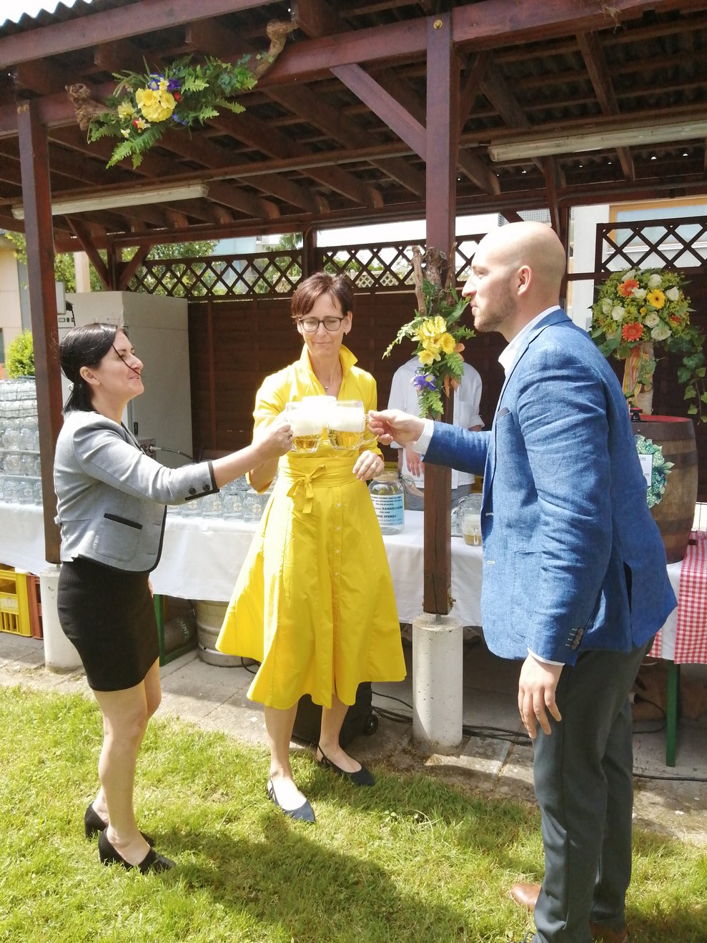 Zwei Damen und ein Herr stoßen mit Bier an.