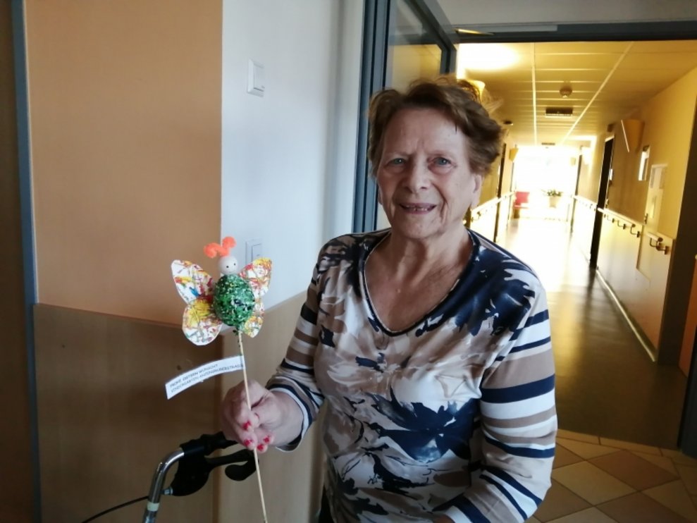 Eine Bewohnerin hält einen Papierschmetterling.