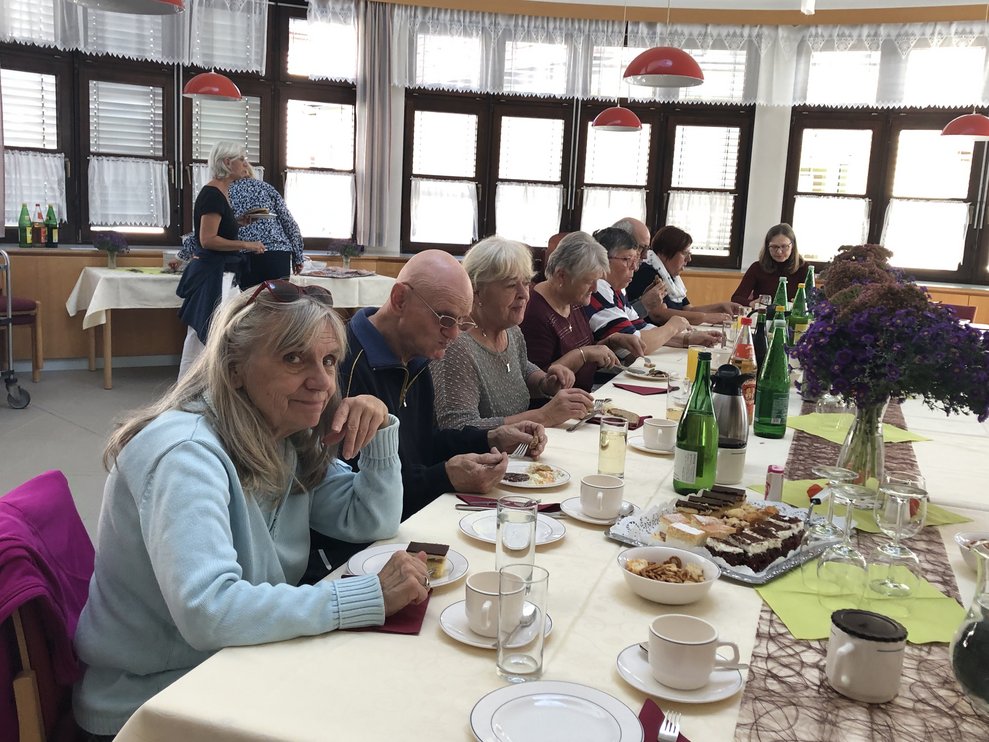 Damen und Herren jausnen am Tisch. 