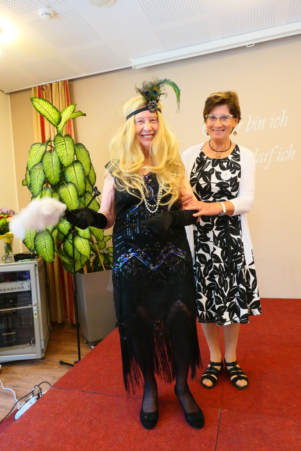 Eine Dame in einem aufregendem schwarzen Kleid mit blonder Perücke und Haarschmuck.