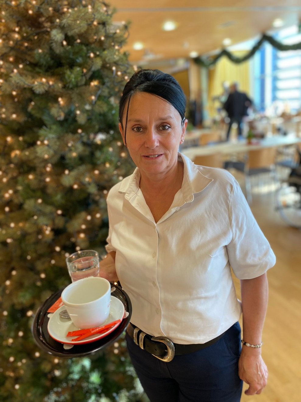 Mitarbeiterin von der Cafeteria bringt Kaffee zu Gäste 