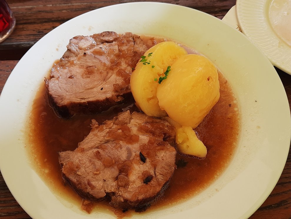 Eine Portion Schweinsbraten mit Knödel und Saft.