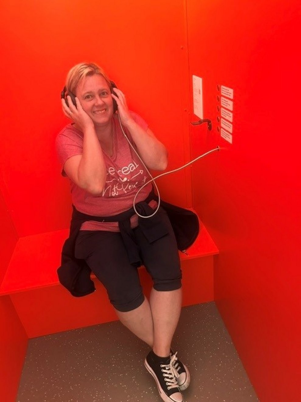 eine Frau mit Kopfhörer in einer roten Kabine