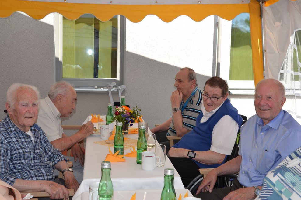 Bewohner sitzen bei einem Tisch.