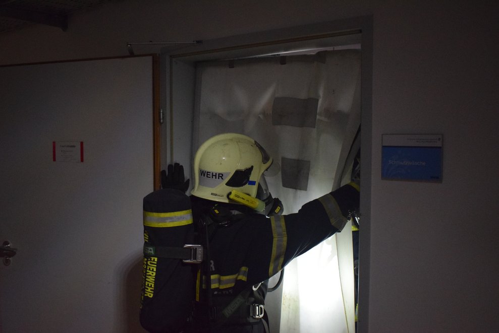 Ein Feuerwehrmann montiert einen Rauchvorhang.