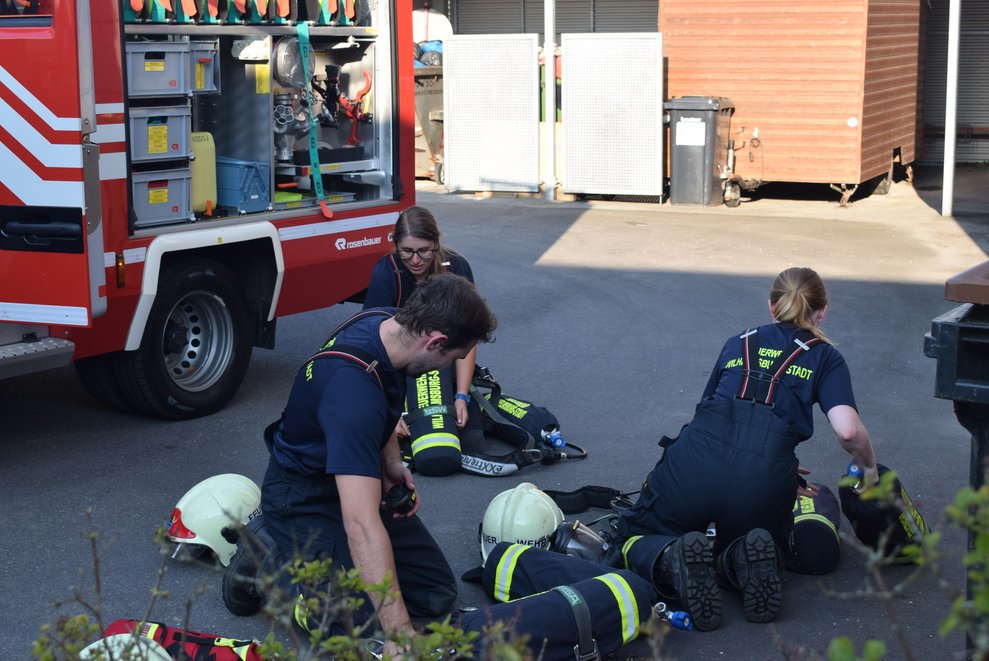 Drei Feuerwehrleute packen die Utensilien zusammen.