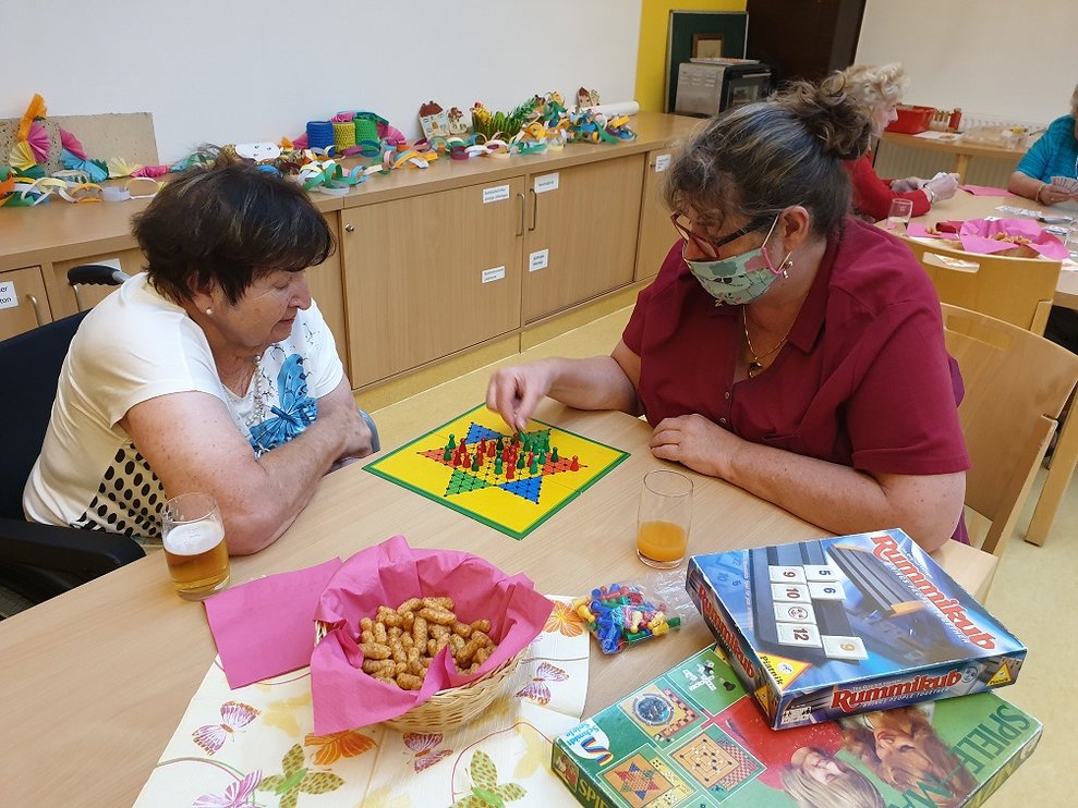 Eine Bewohnerin und eine Betreuerin spielen ein Brettspiel.