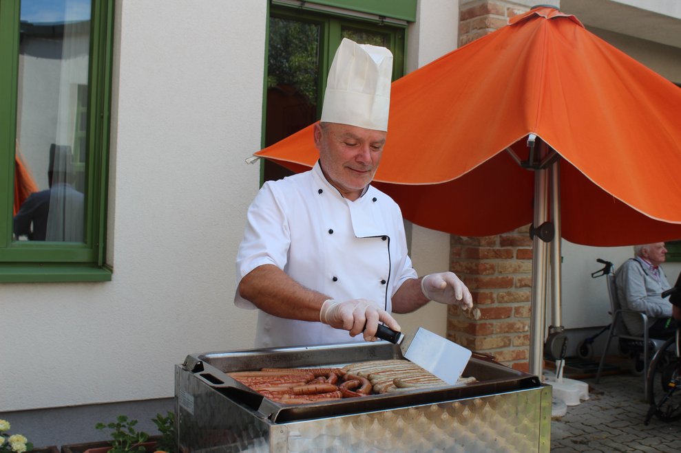 Küchenleiter Christian Thüringer legt die Cevapcici und Würstel auf den Grill