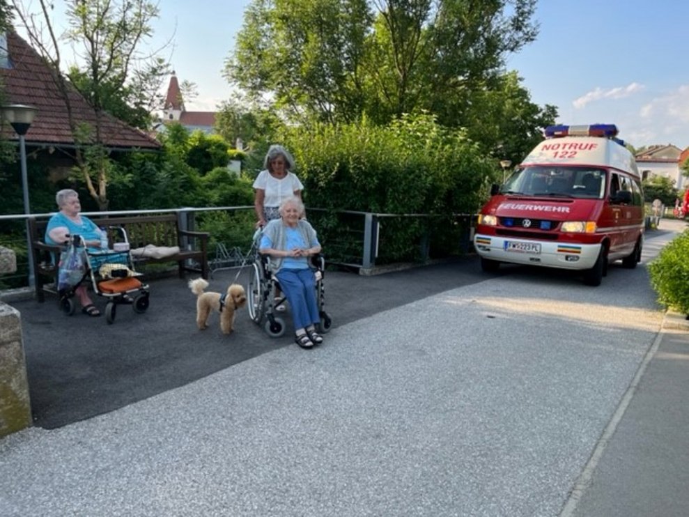 Drei Damen im Freien, im Hintergrund sieht man ein Feuerwehrauto.