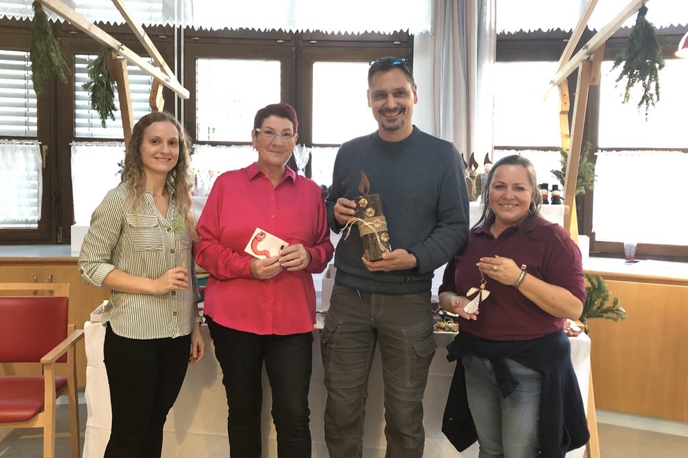 Ein Mann und drei Frauen vor einem Verkaufsstand.