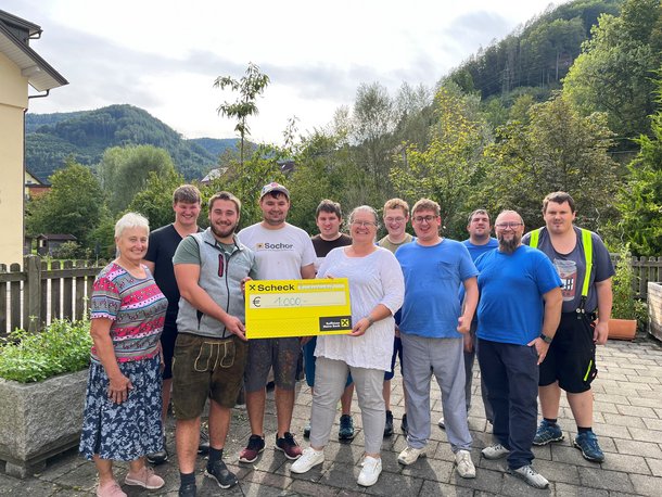Eine Gruppe von Personen hält ein großes Plakat in den Händen.