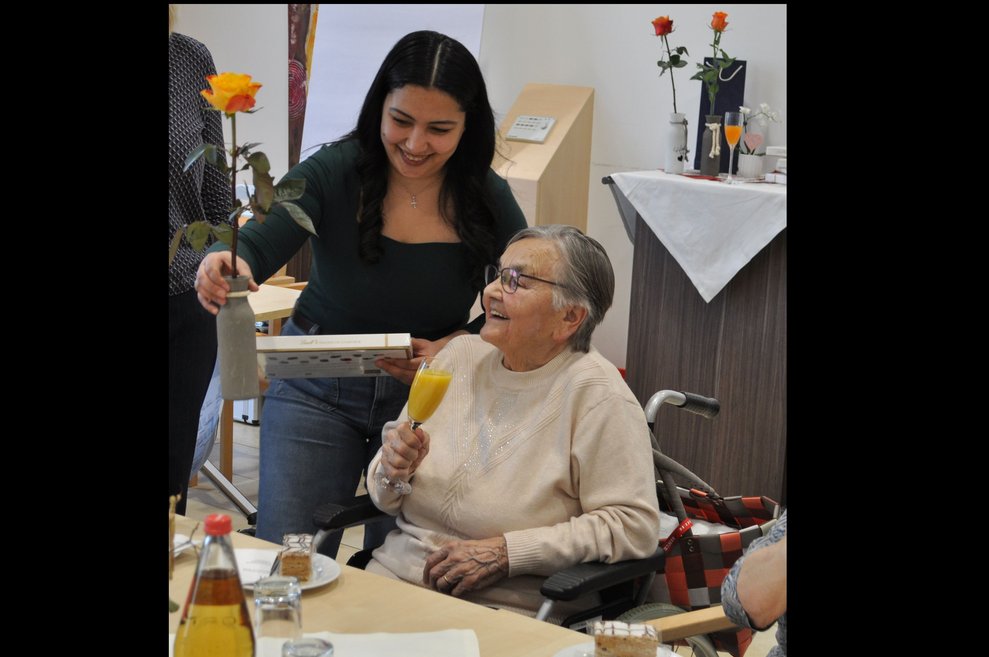 eine Dame gratuliert einer älteren Frau zum Geburtstag