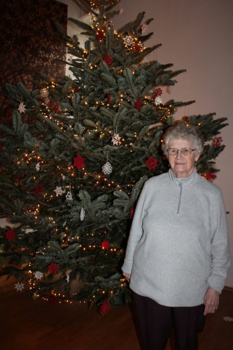 Eine Bewohnerin steht beim Christbaum.