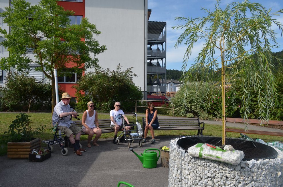 Bewohner sitzen auf Bank vor dem Baum